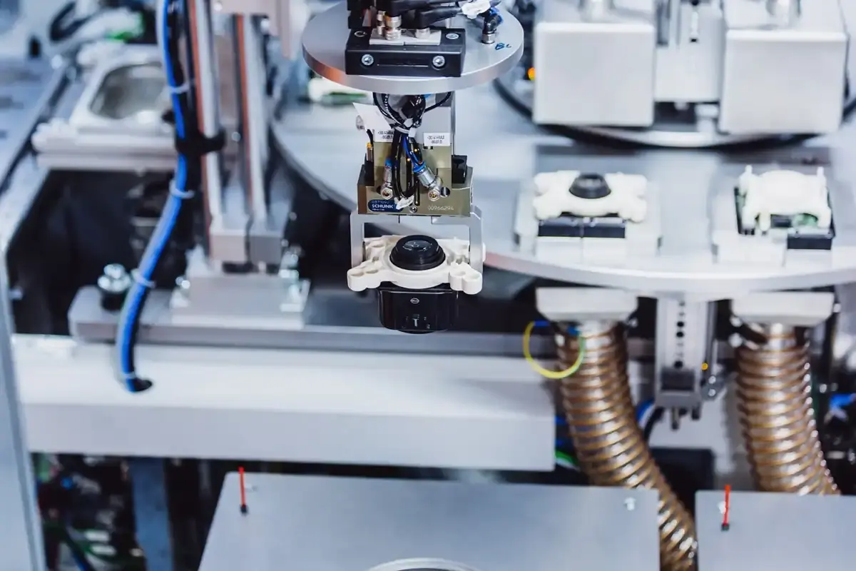 Präzisions-Greifsystem einer vollautomatischen AWM-Montagelinie beim exakten Positionieren und Fügen von LED-Scheinwerfermodulen für die Automobilindustrie.