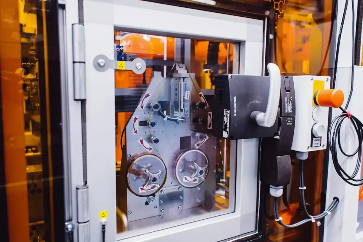 Automatisiertes Bandspulensystem zur Materialzuführung mit Führungrollen, Schmersal-Sicherheitsschalter und transparenter Wartungsklappe im Sondermaschinenbau der AWM Arnstadt.