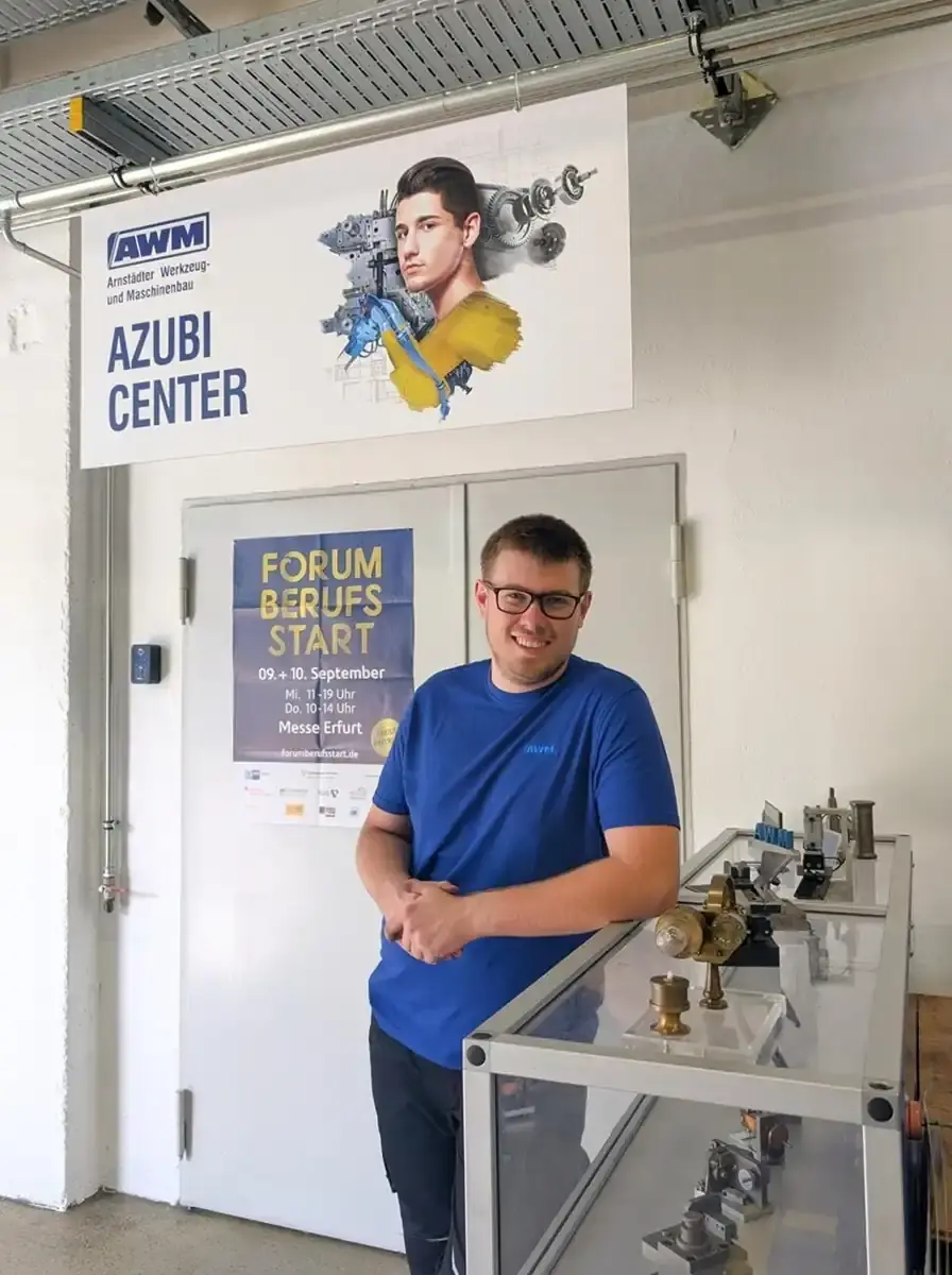 AWM employee in the Azubi Center in front of a poster for the Forum Berufsstart Erfurt trade fair.